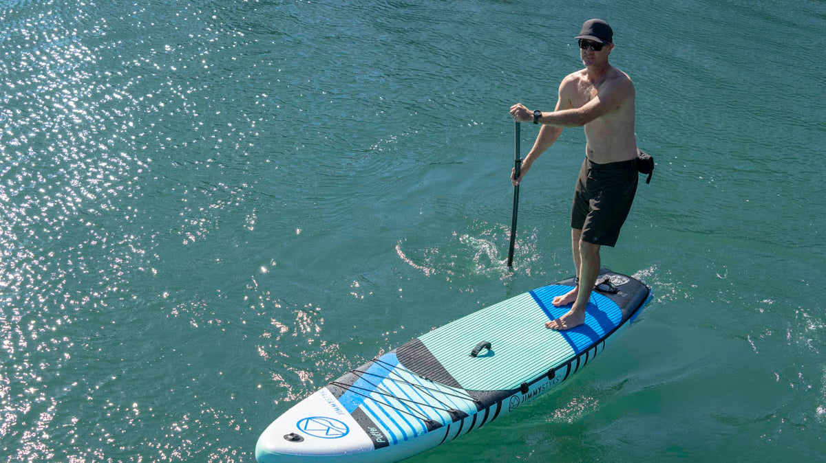 A man is paddle boarding with Jimmy Styks inflatable SUPs