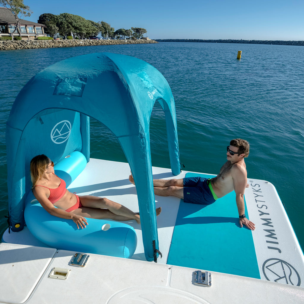 A man and a woman is floating on the water with Jimmy Styks water mat