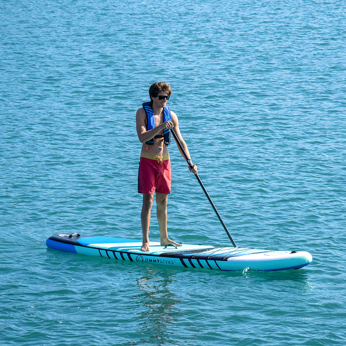 A man is paddling with Jimmy Styks inflatable stand up paddle board